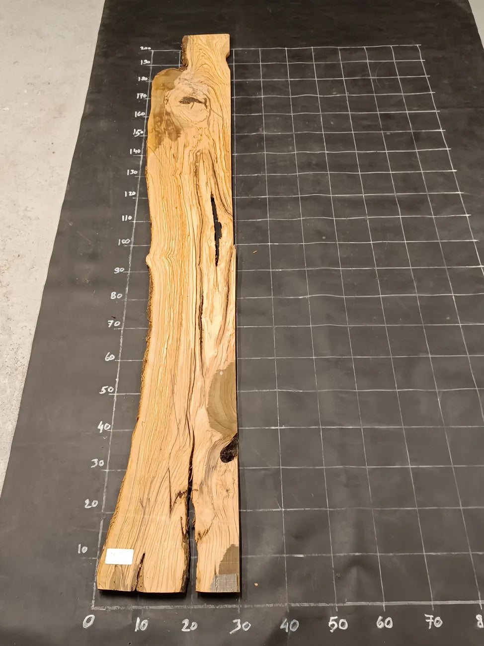 Planche bois d'olivier rabotée 2 cm à bord naturel, 190×30 cm, réf P03, sur tapis quadrillé 10 cm — recto