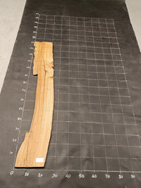 Planche bois d'olivier rabotée 2 cm à bord naturel, 135×30 cm, réf P37, sur tapis quadrillé 10 cm — verso