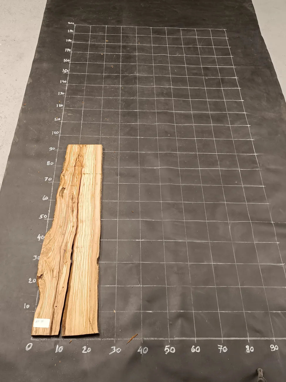Planche bois d'olivier rabotée 2 cm à bord naturel, 140×30 cm, réf P34, sur tapis quadrillé 10 cm — recto