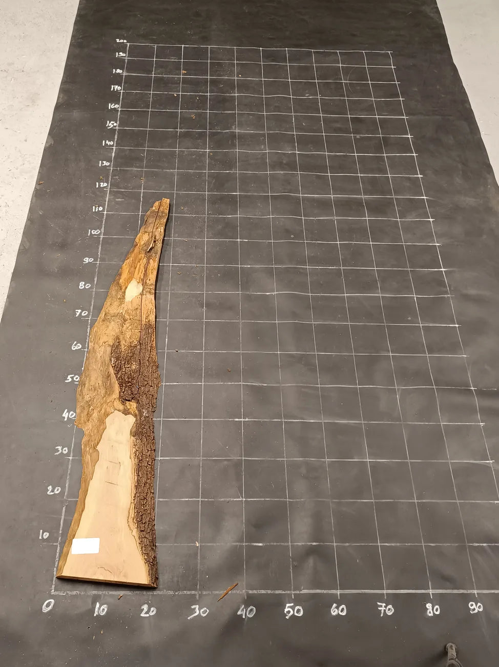 Planche bois d'olivier rabotée 2 cm à bord naturel, 165×30 cm, réf P35, sur tapis quadrillé 10 cm — recto