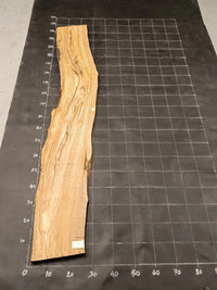 Planche bois d'olivier rabotée 2 cm à bord naturel, 180×28 cm, réf P18, sur tapis quadrillé 10 cm — verso