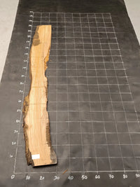 Planche bois d'olivier rabotée 2 cm à bord naturel, 180×28 cm, réf P29, sur tapis quadrillé 10 cm — verso