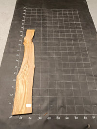 Planche bois d'olivier rabotée 2 cm à bord naturel, 180×28 cm, réf P33, sur tapis quadrillé 10 cm — recto