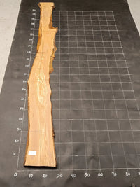 Planche bois d'olivier rabotée 2 cm à bord naturel, 185×25 cm, réf P15, sur tapis quadrillé 10 cm — recto