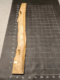 Planche bois d'olivier rabotée 2 cm à bord naturel, 185×28 cm, réf P04, sur tapis quadrillé 10 cm — recto