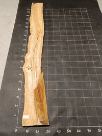 Planche bois d'olivier rabotée 2 cm à bord naturel, 185×28 cm, réf P07, sur tapis quadrillé 10 cm — verso