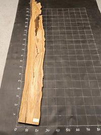 Planche bois d'olivier rabotée 2 cm à bord naturel, 185×28 cm, réf P09, sur tapis quadrillé 10 cm — verso