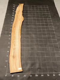 Planche bois d'olivier rabotée 2 cm à bord naturel, 185×28 cm, réf P22, sur tapis quadrillé 10 cm — recto