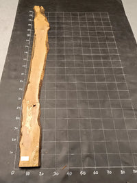 Planche bois d'olivier rabotée 2 cm à bord naturel, 185×28 cm, réf P24, sur tapis quadrillé 10 cm — verso