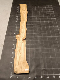 Planche bois d'olivier rabotée 2 cm à bord naturel, 185×30 cm, réf P01, sur tapis quadrillé 10 cm — verso