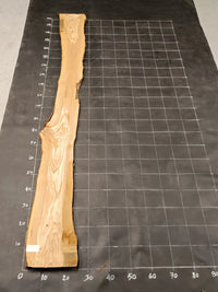 Planche bois d'olivier rabotée 2 cm à bord naturel, 185×30 cm, réf P28, sur tapis quadrillé 10 cm — verso