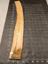Planche bois d'olivier rabotée 2 cm à bord naturel, 190×28 cm, réf P05, sur tapis quadrillé 10 cm — verso