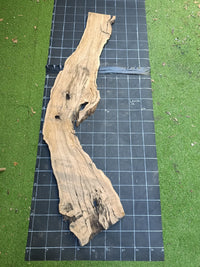 Plateau bois d'olivier brut à bord vivant 140×70 cm, réf N°012, sur tapis quadrillé 10 cm — verso