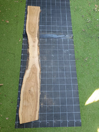 Plateau bois d'olivier brut à bord vivant 200×30 cm, réf N°027, sur tapis quadrillé 10 cm — recto