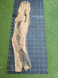 Plateau bois d'olivier brut à bord vivant 190×50 cm, réf N°029, sur tapis quadrillé 10 cm — verso